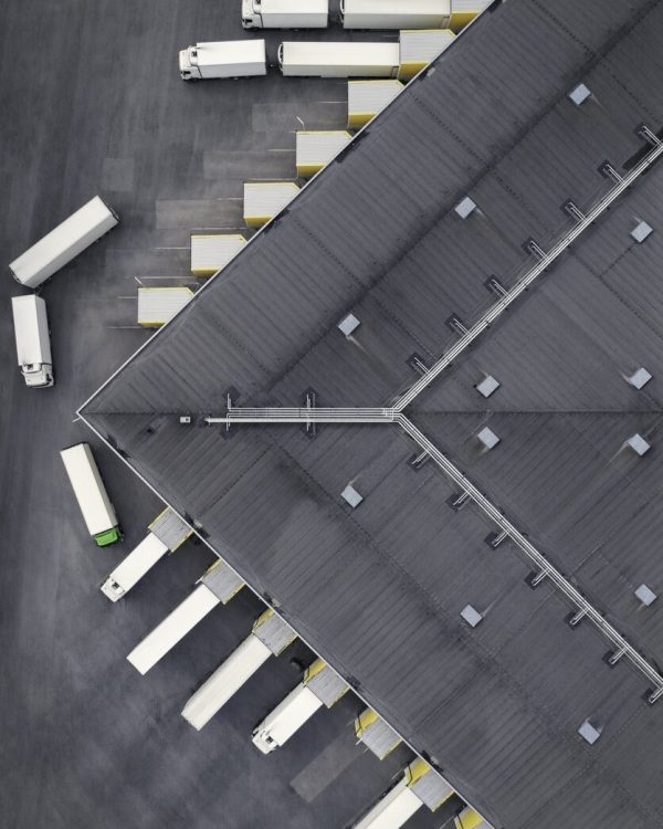 Aerial view of a large distribution warehouse with loading docks and many trucks.